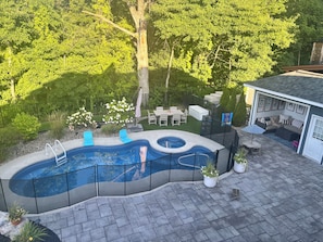 Ein Garten mit Schwimmbad, Terrassenmöbeln und einer überdachten Sitzgelegenheit.