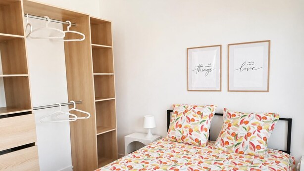 Ein Schlafzimmer mit einem Bett, einem Kleiderschrank und zwei gerahmten, motivierenden Sprüchen an der Wand.