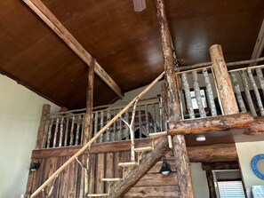 A rustic wooden staircase with a wooden railing, a wooden ceiling, and a wall-mounted light fixture. - Creekside cabin in heart of the Cherokee National Forest on 4 private acres (Reliance)
