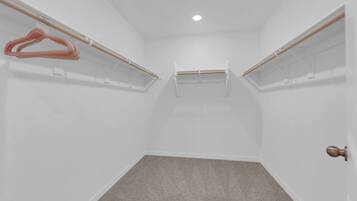 Um quarto com paredes brancas, um tapete cinza e uma porta com puxador redondo.