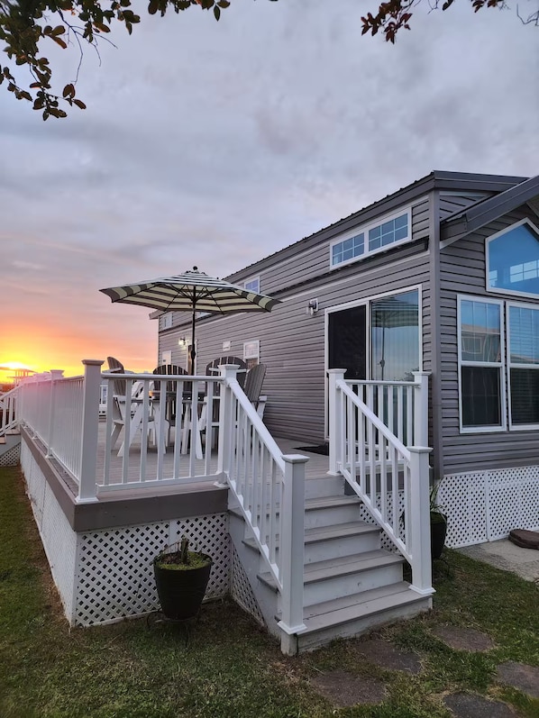 A mobile home with a deck, outdoor furniture, and a potted plant.