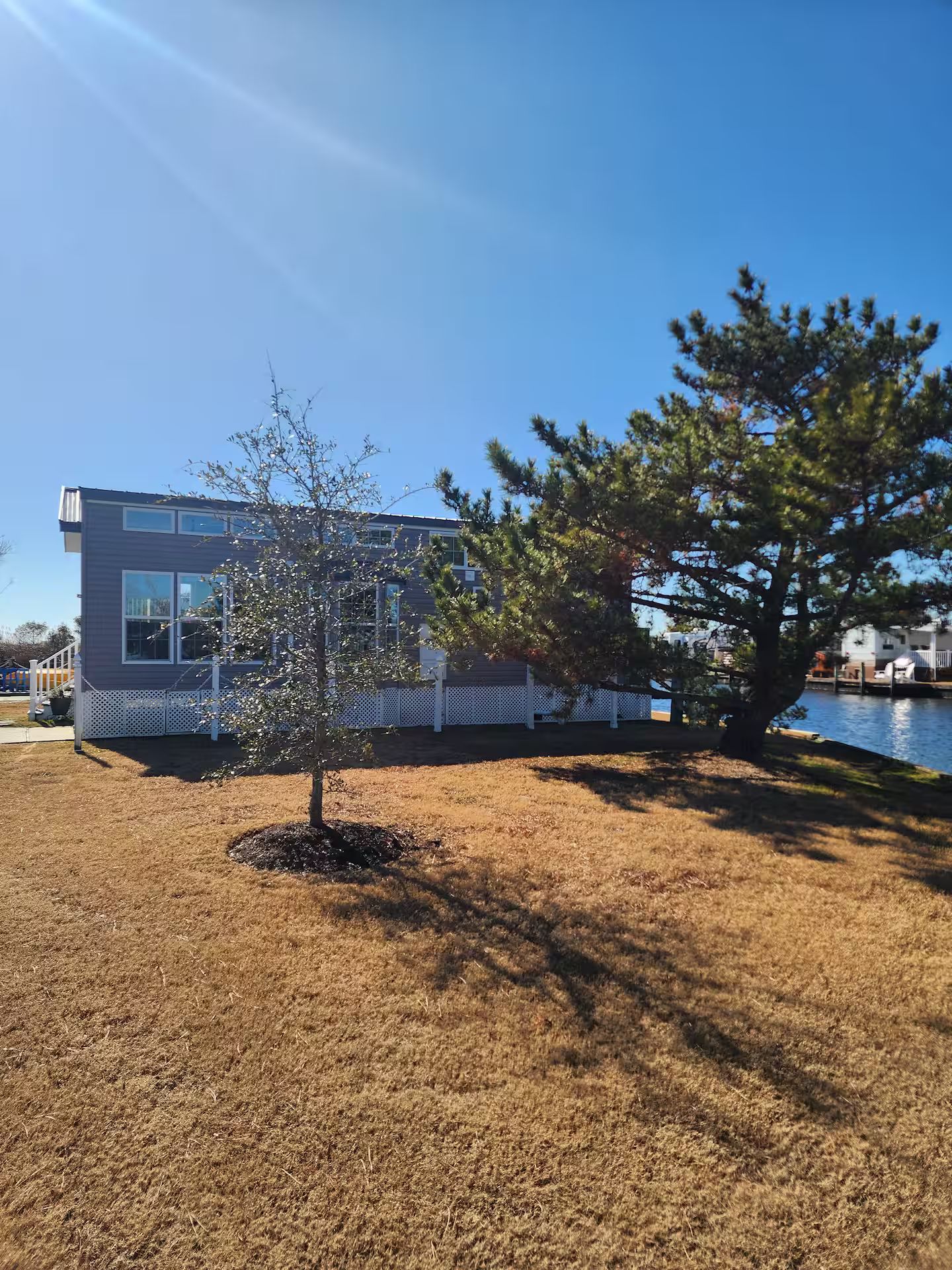 A modern two-story building with a white fence and a tree in front.