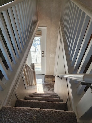 Una escala amb barana, fons de moqueta i una porta al final que dona a l'exterior.