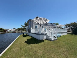 A waterfront property with a dock, a covered deck, and a grassy lawn.
