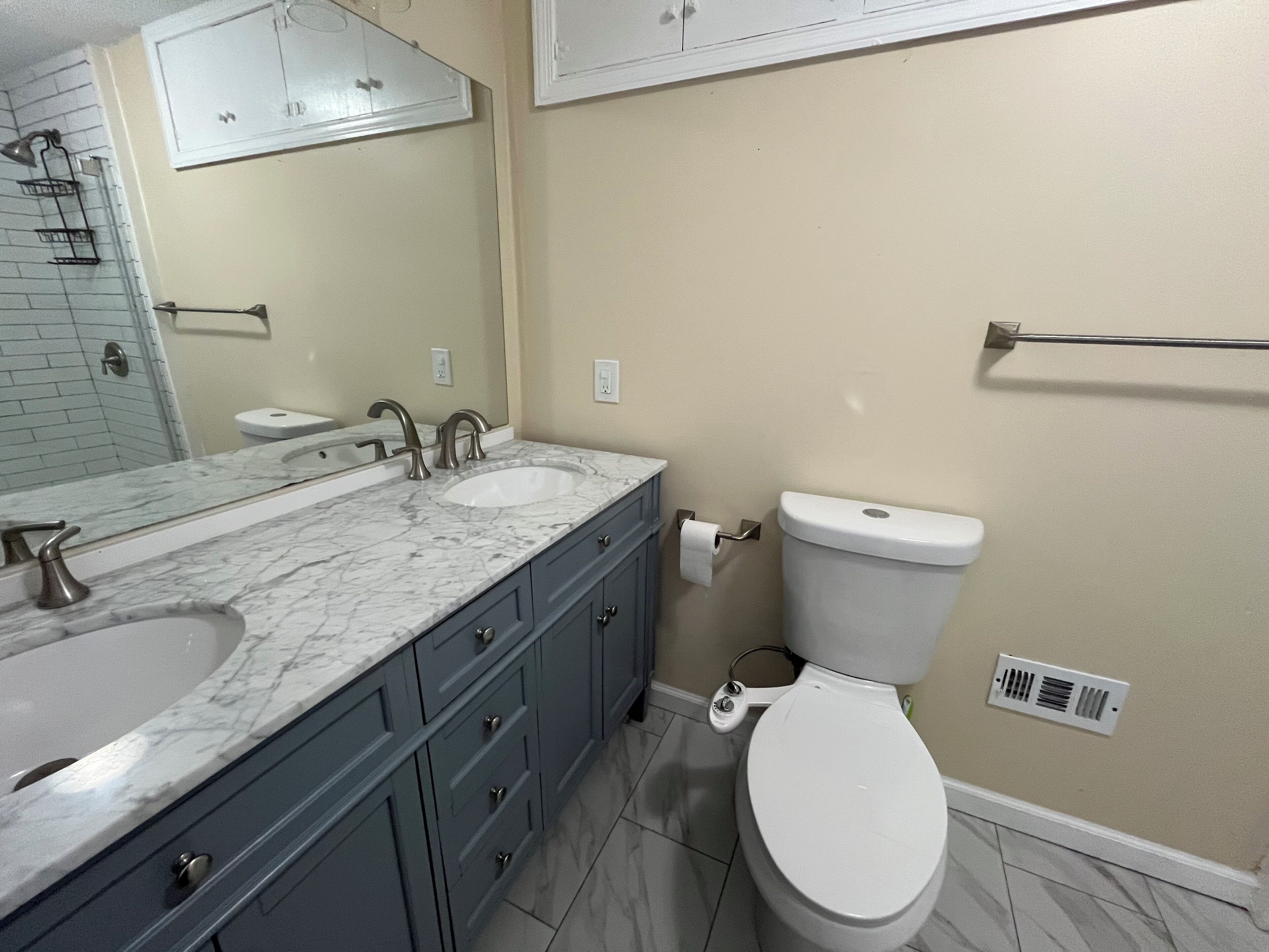 A bathroom with two sinks, a toilet, and a shower area.