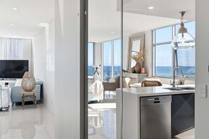 Una sala de estar moderna con un televisor grande, un comedor con vistas y una cocina equipada con lavavajillas.