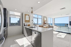 Una cocina moderna con una isla central, ventanas amplias y vista al mar.