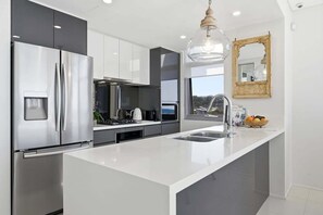 Una cocina moderna con un refrigerador de acero inoxidable, un horno empotrado y una isla grande con un fregadero.