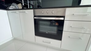 Une cuisine équipée d’un four encastré, de meubles en acier inoxydable et d’un plan de travail noir.
