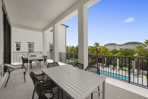 Ein überdachter Außenbereich mit Pool, Esstisch und Stühlen.