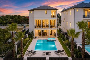 Ein zweistöckiges Haus mit Pool, Außenbereich mit Sitzgelegenheiten und einem Balkon.