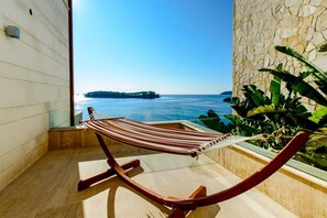 Eine Hängematte auf einem Balkon mit Blick auf das Meer und eine entfernte Insel.