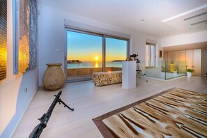 Ein modernes Interieur mit einer großen Glastür, die auf einen Balkon mit Sonnenuntergangsblick führt.