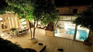 An indoor pool area with a stone wall, a dining area with a table and chairs, and a lounge area with a sofa and a small table. - Villa Ljuba - Private villa with pool, Hvar (Hvar)
