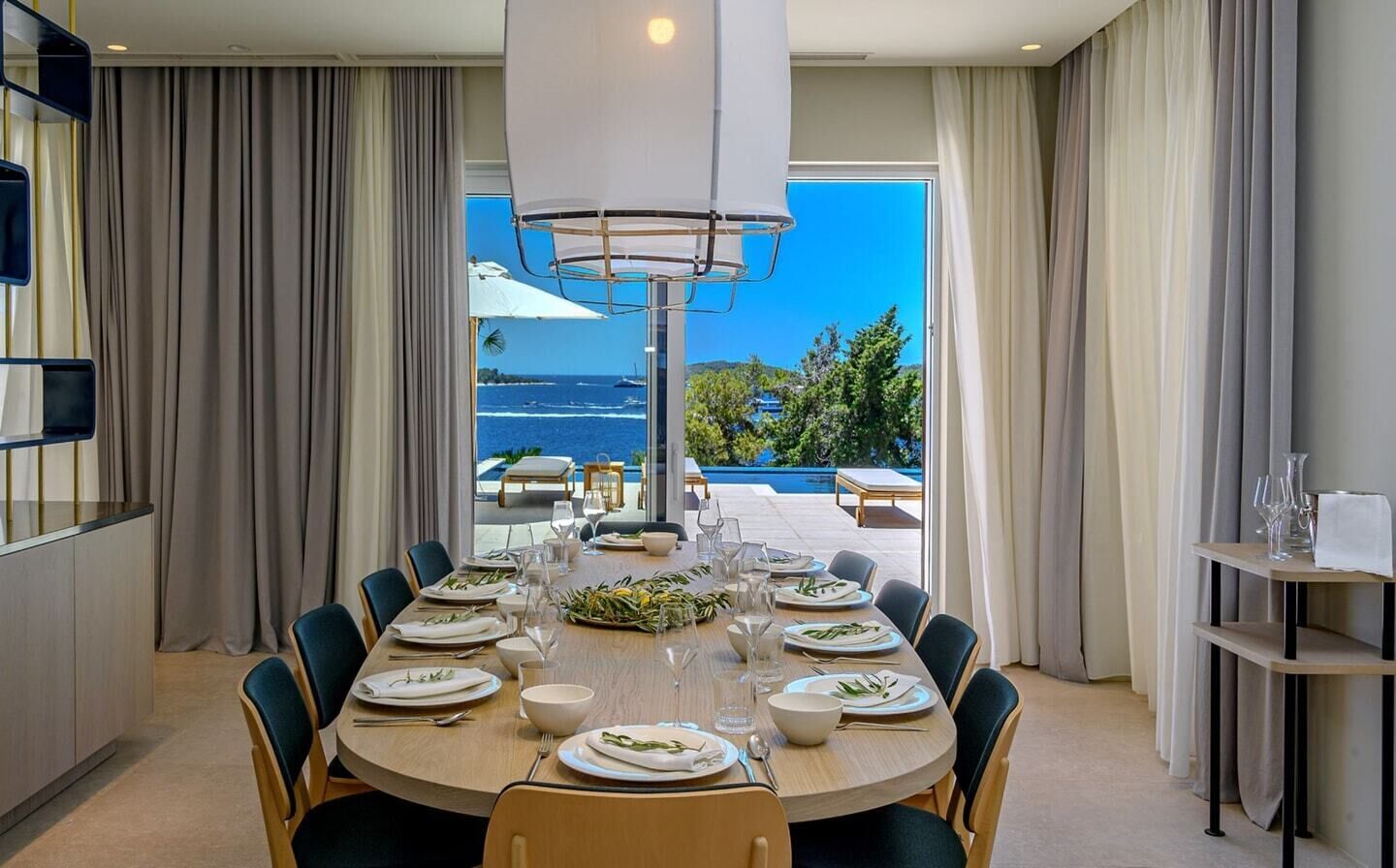 Ein Esszimmer mit Meerblick, ein runder Tisch gedeckt für eine Mahlzeit und ein großes Fenster.
