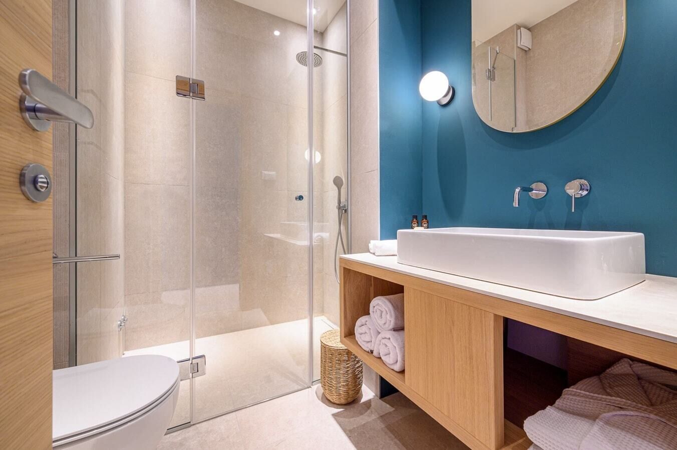 Ein modernes Badezimmer mit einer gläsernen Duschkabine, einem weißen Waschbecken und einer blauen Akzentwand.