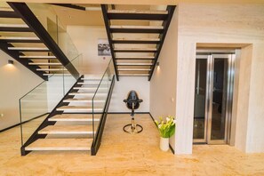 Ein modernes Interieur mit einer Wendeltreppe aus Glas, einem runden Tisch mit einem Stuhl und einem Blumentopf.