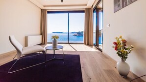 Een moderne kamer met een groot raam, een bank, een bijzettafeltje en een bloemenvaas.