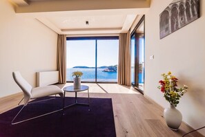 Ein modernes Zimmer mit großem Fenster, einer Couch, einem kleinen Tisch und einem Blumenstrauß.