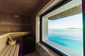 Una sauna con interior de madera y vista al mar a través de un ventanal grande.