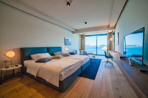 Ein Hotelzimmer mit einem großen Bett, einem Schreibtisch und Blick aufs Meer.