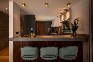 A modern kitchen with a bar area, three bar stools, and a large window. - Villa Spasenka, Private with pools (Dubrovnik)