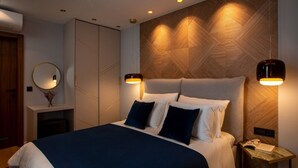 Un dormitorio moderno con una cama grande, lámparas de noche, un espejo y una pared decorativa de madera.