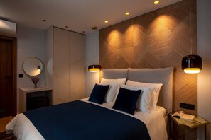 Ein modernes Schlafzimmer mit einem großen Bett, Nachttischlampen, einem Spiegel und einer Wand mit Holzakzenten.
