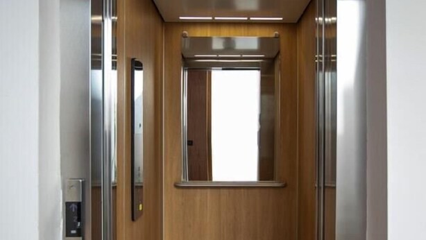 Un ascensor con interior de madera y puerta de metal.