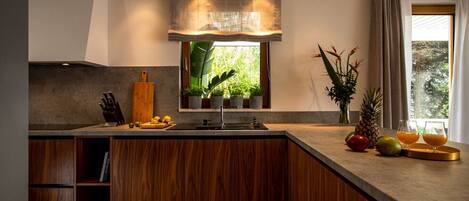 A modern kitchen with a wooden island, built-in cabinets, and a window with a view of greenery.