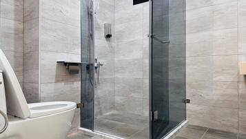 A modern bathroom with a glass-enclosed shower, a toilet, and a towel rack.