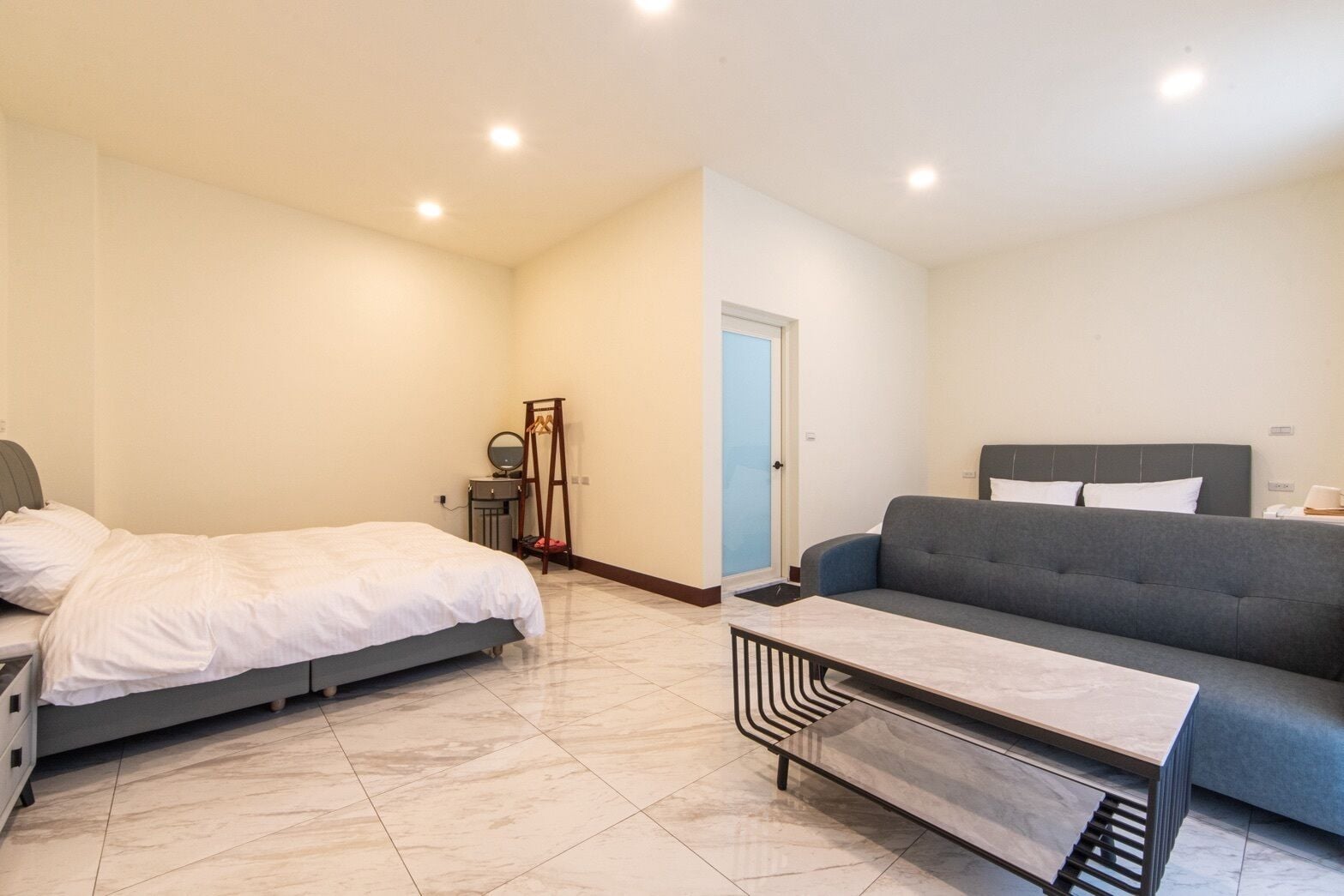 A bedroom with a bed, a dresser, a mirror, and a door.