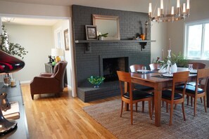 A dining area with a brick fireplace, wooden dining table, chairs, and a chandelier. - Modern 3 bedroom in nice location.   Less than 2 miles to Downtown. (Boulder)