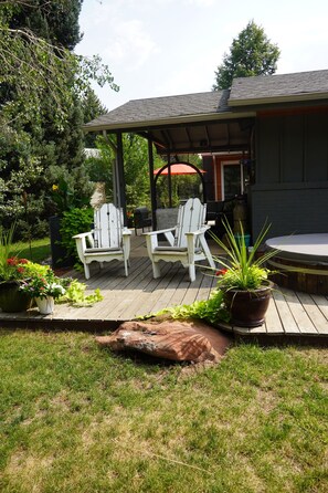 A covered outdoor seating area with two Adirondack chairs, a hot tub, and potted plants. - Modern 3 bedroom in nice location.   Less than 2 miles to Downtown. (Boulder)