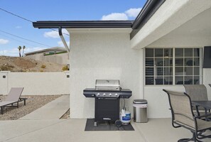 Eine Terrasse mit Grill, Sitzgelegenheit und Mülleimer.