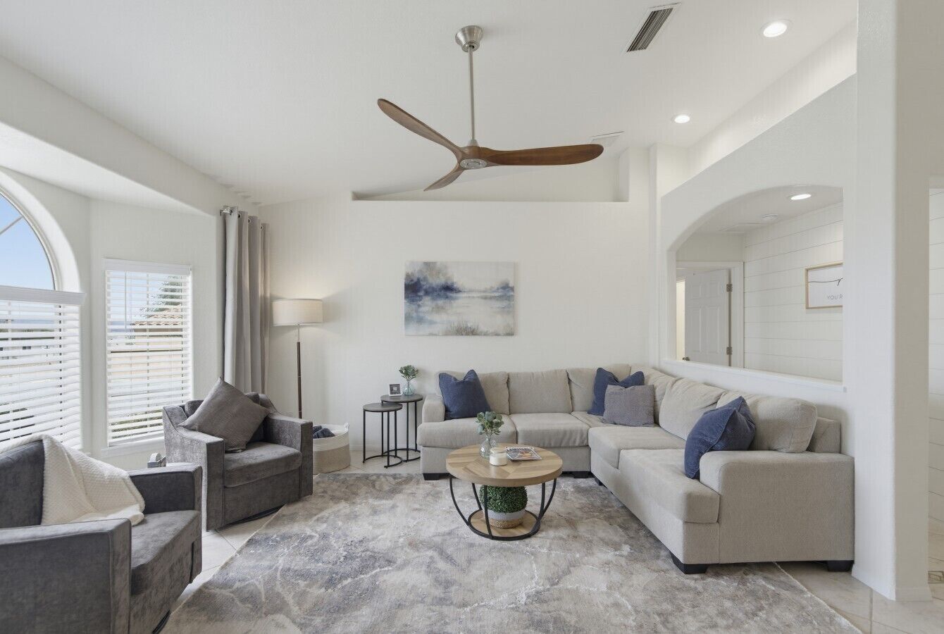 A modern living room with a ceiling fan, two sofas, a coffee table, and a rug.