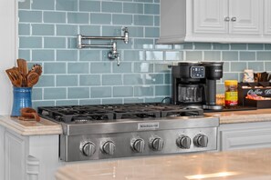 A kitchen with a stainless steel stove, a coffee maker, and a spice rack. - Luxury Pet Friendly Gulf Retreat with Pool + Hot Tub, Game Room and Putting Green | Sleeps 22 (Port Bolivar)
