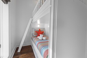 A narrow hallway leading to a bedroom with a bed, a starfish decoration, and a rolled towel. - Luxury Pet Friendly Gulf Retreat with Pool + Hot Tub, Game Room and Putting Green | Sleeps 22 (Port Bolivar)