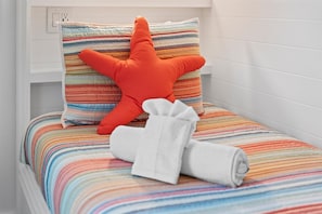 A bed with a striped bedspread, a rolled white towel, and a large orange pillow. - Luxury Pet Friendly Gulf Retreat with Pool + Hot Tub, Game Room and Putting Green | Sleeps 22 (Port Bolivar)