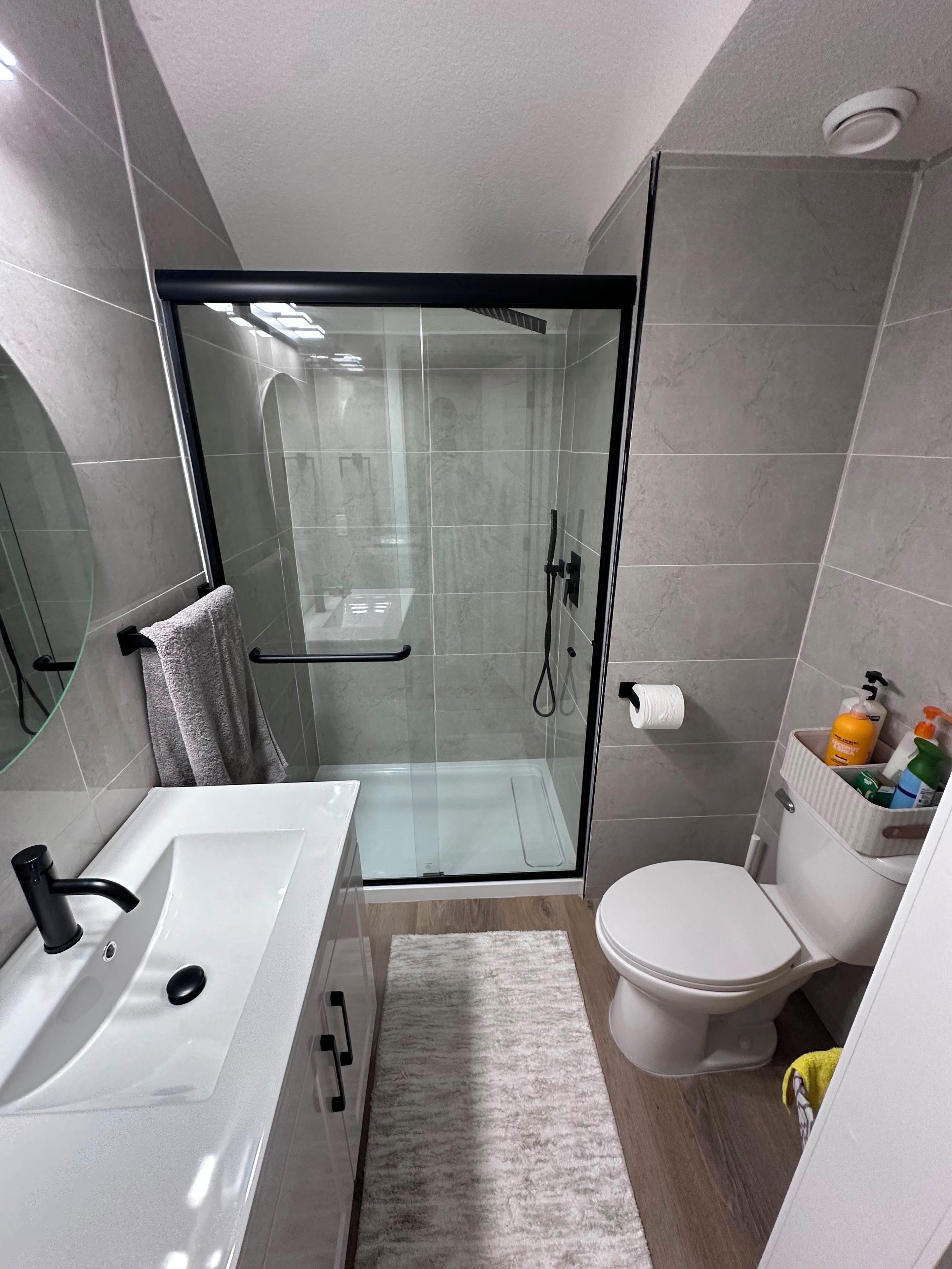 Ein modernes Badezimmer mit einer Duschkabine, einem weißen Waschbecken und einer Toilette.