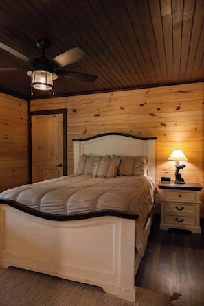 A bedroom with a bed, a nightstand, a lamp, and a ceiling fan. - Heated Pool, 2 Firepits, Game Room, Theater, 3200 SQFT (Sevierville)