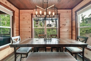 Ein Holzinterieur mit Esstisch, Stühlen und einer Pendelleuchte.
