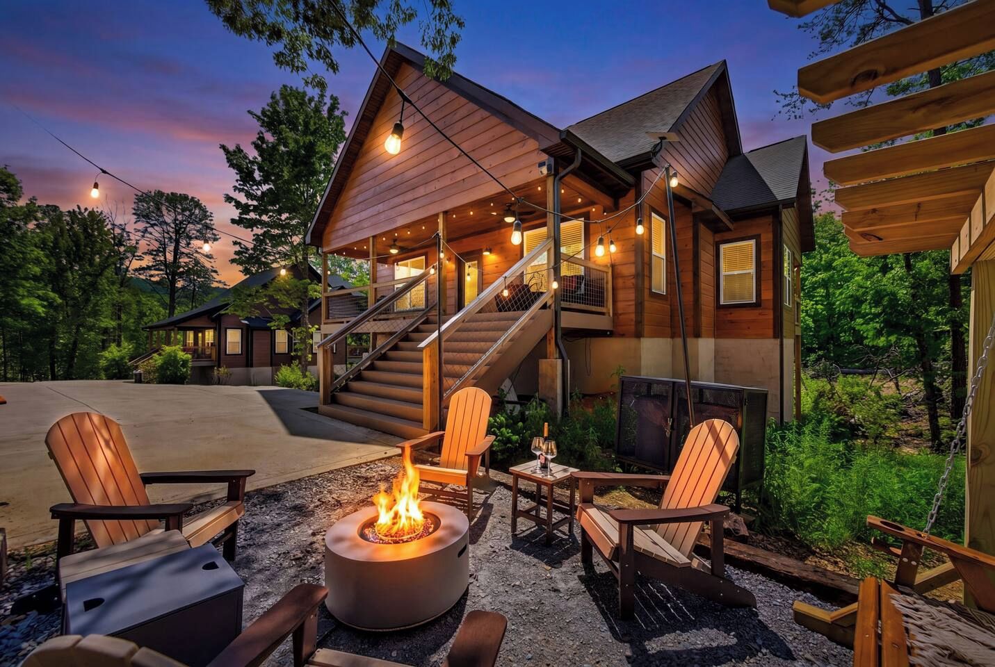 Una cabaña de madera con chimenea, asientos exteriores y una escalera que lleva a un nivel superior.