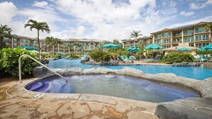 Un área de piscina hotelera con varias piscinas, sillas de descanso y sombrillas.