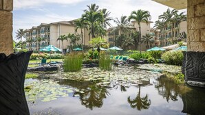 Un patio de hotel con fuente de agua, palmeras y piscina.