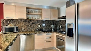 Eine moderne Küche mit Edelstahlgeräten, Granit Arbeitsplatten und Holzschränken.