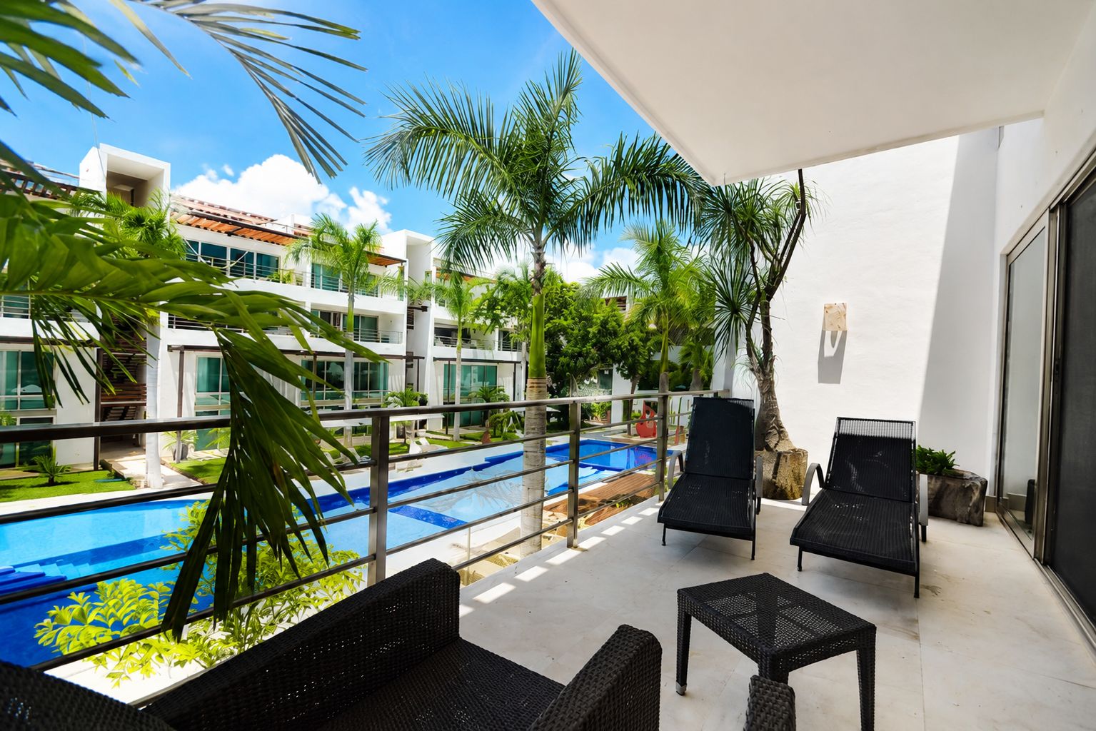 A balcony with a pool, outdoor furniture, and a view of a modern building.