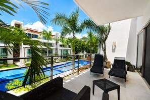 Un balcon avec une piscine, du mobilier d’extérieur et une vue sur un immeuble moderne.