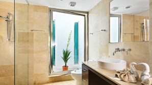 Ein modernes Badezimmer mit Duschkabine aus Glas, einem weißen Waschbecken und einer Topfpflanze.
