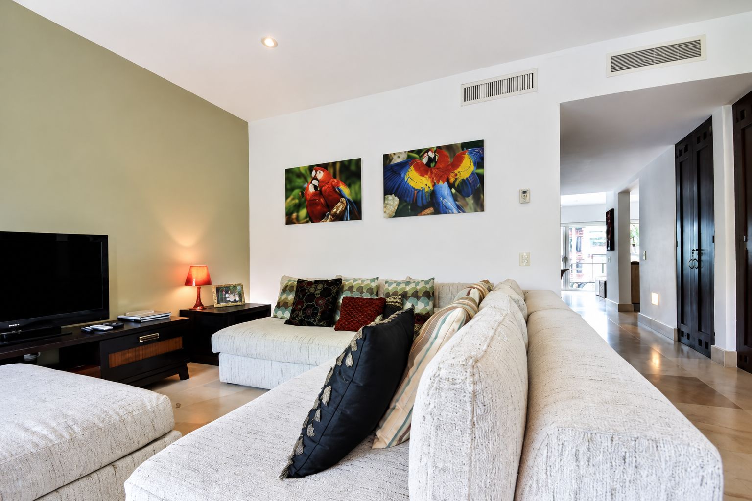 Ein modernes Wohnzimmer mit einem Flachbildfernseher, einer Couch und zwei an der Wand befestigten Bildern.